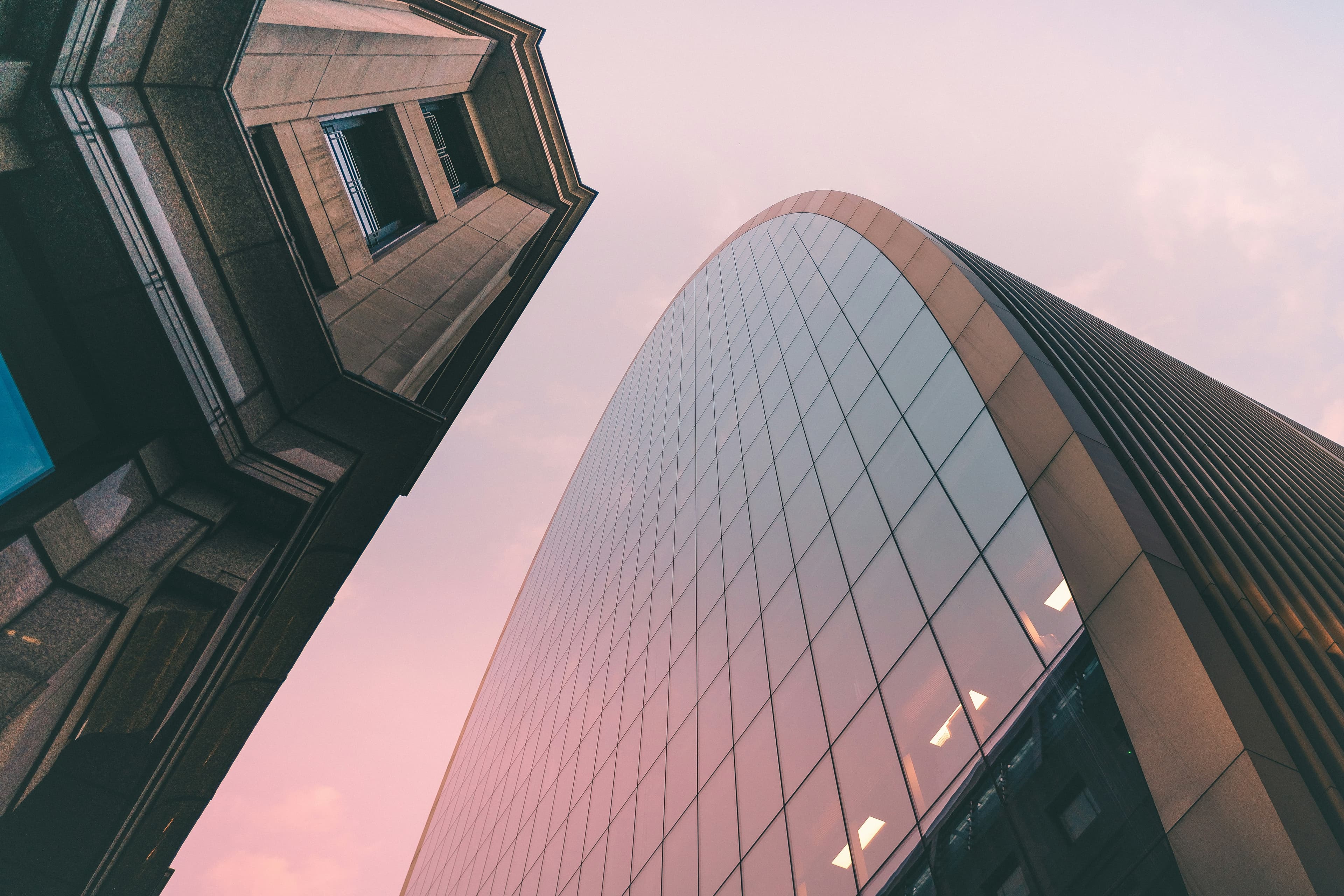 Curved glass tower framed by neighbouring architecture at dusk